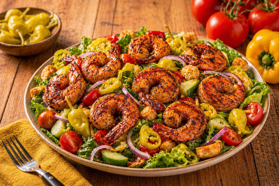 blackened jumbo gulf shrimp salad in a bowl on a dark wood table.