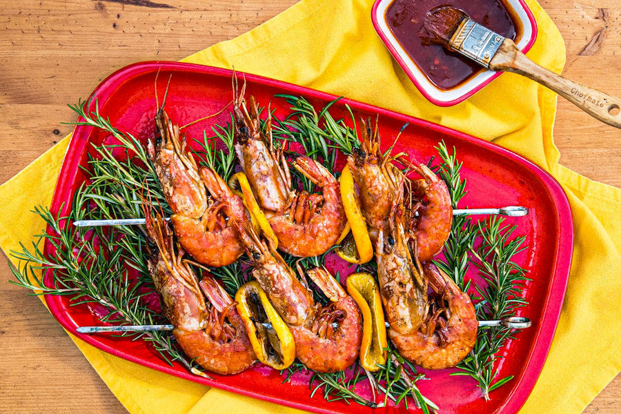 Grilled Red-Hot Tiger Prawns on a red plater on a wood table.