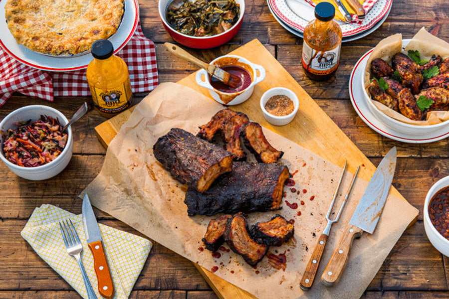 memphis bbq dry rub ribs on a wood cutting board on a picnic table with sides.