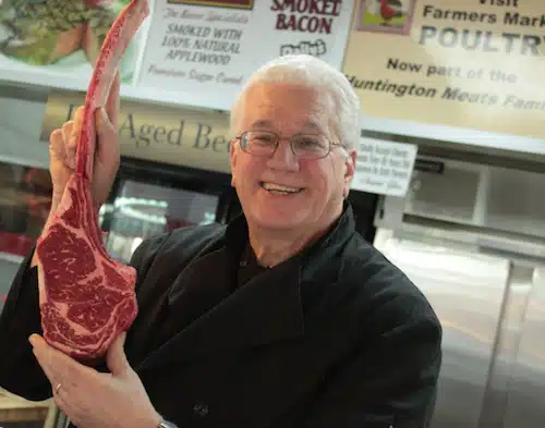 Huntington Meats Owner Jim Cascone holds up large cut of meat